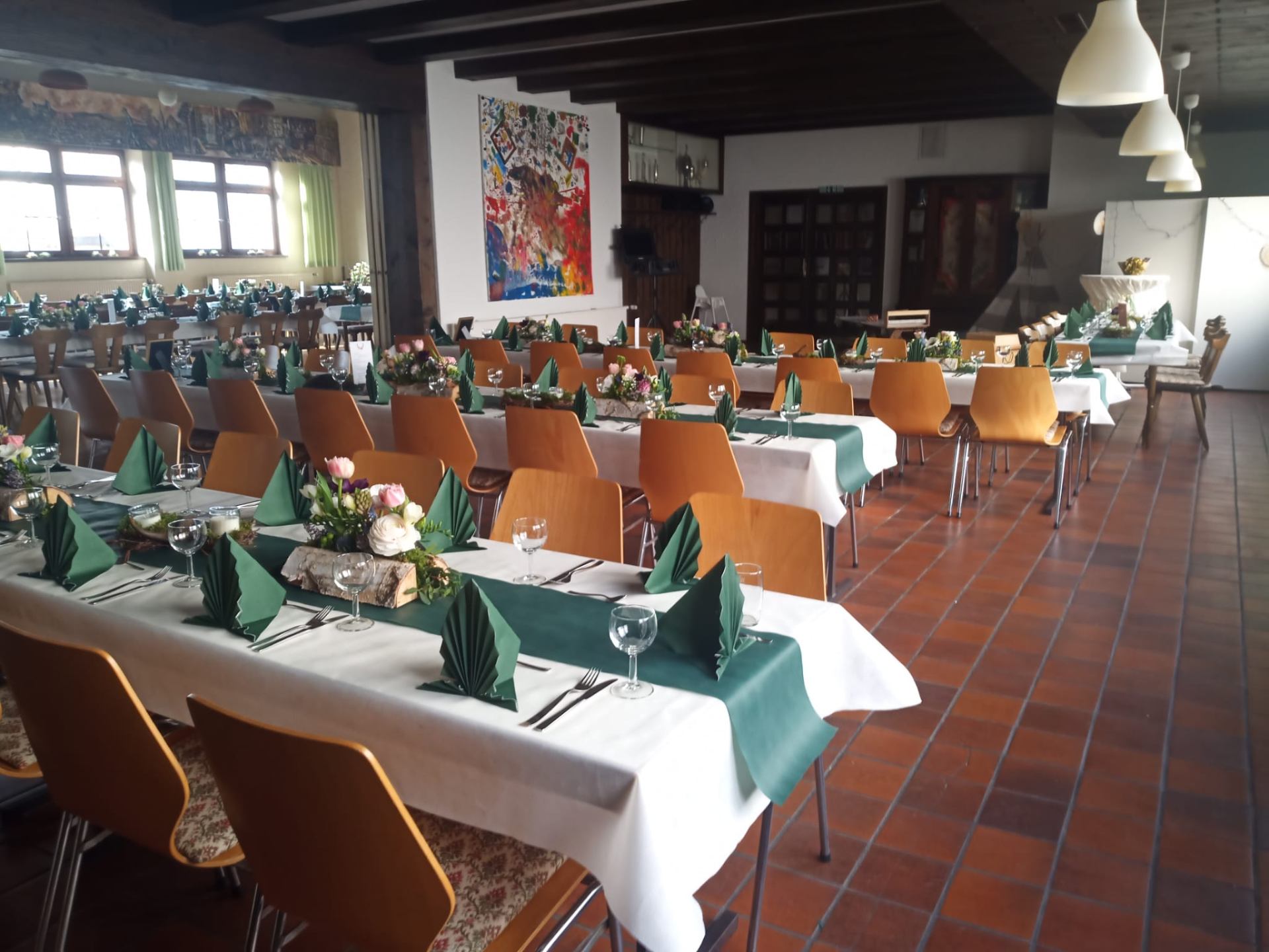Gedeckte Tische mit grüner Dekoration im Saal